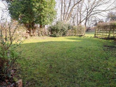 A grassy garden area with trees and fences at Tile Rouge in Wooler