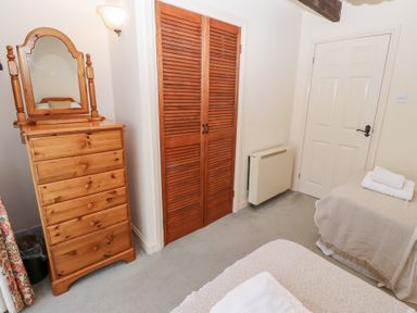 A bedroom with a wooden dresser with mirror wooden closet doors and a bed with folded towels at Pansy Plot in Akeld near Wooler