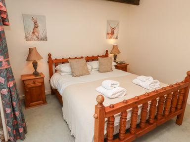 A bedroom with a wooden double bed two nightstands lamps and wall art at Pansy Plot in Akeld near Wooler