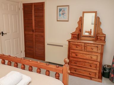 A bedroom with wooden bed frame dresser with mirror closet doors and a framed picture at Pansy Plot Akeld near Wooler