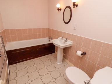 A bathroom with a bathtub sink toilet and wall mirror at Pansy Plot Akeld near Wooler