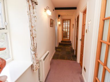 A hallway with floral curtains and wooden doors at The Columbine in Akeld near Wooler