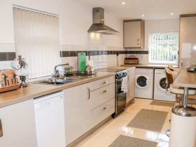 A kitchen with a sink stove washing machine and dishwasher at Lane Cottage in Ballycullane County Wexford