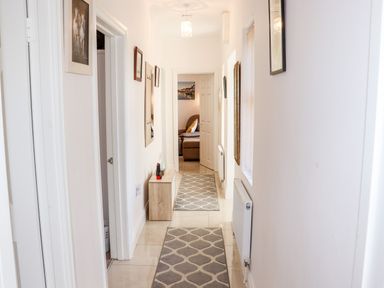 A hallway with white walls and two patterned rugs with a wooden bench and framed pictures at Lane Cottage in Ballycullane County Wexford