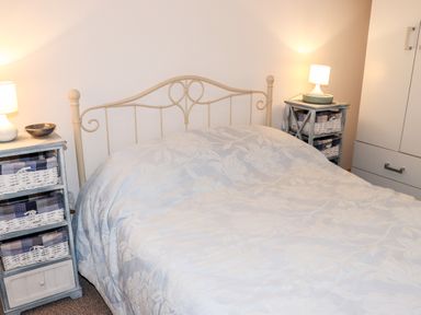 A bedroom with a bed covered with a floral bedspread and two bedside tables with lamps at Lane Cottage in Ballycullane County Wexford