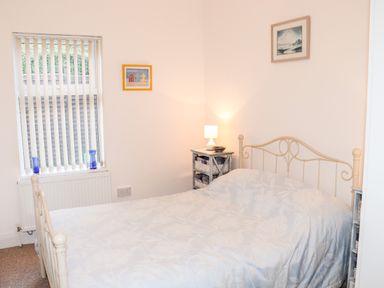 A bedroom with a metal bed frame bedside tables with baskets a lamp and two paintings on the walls at Lane Cottage Ballycullane County Wexford