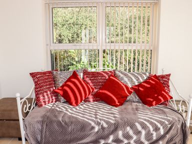 A daybed with multiple cushions in front of a window with vertical blinds at Lane Cottage Ballycullane County Wexford