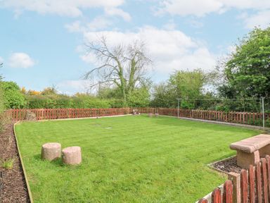 A fenced garden area with grass lawn stone seats and a bench at Lane Cottage in Ballycullane County Wexford