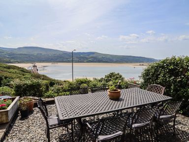 An outdoor area with a table and chairs overlooking a river at 5 Porkington Terrace in Barmouth