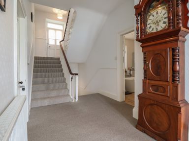 A hallway with a staircase and a clock at 5 Porkington Terrace Barmouth
