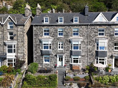A stone house with windows and outdoor furniture at 5 Porkington Terrace Barmouth
