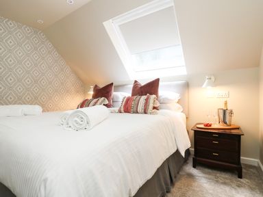 A bedroom with two pillows and rolled towels on a bed and a bedside table with a champagne bucket at Robins Nest at The Shire Inn in Killivose near Camborne