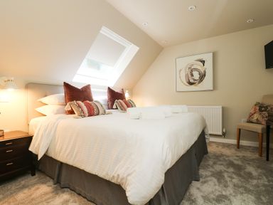 A bedroom with a large bed pillows bedside table and a chair at Robins Nest at The Shire Inn in Killivose near Camborne