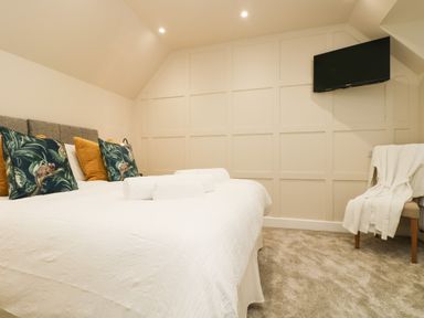 A bedroom with a bed with pillows and rolled towels a tv on the wall and a chair with a robe at Robins Nest at The Shire Inn Killivose near Camborne