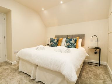 A bedroom with a bed featuring patterned pillows and bedside tables with lamps at Robins Nest at The Shire Inn in Killivose near Camborne