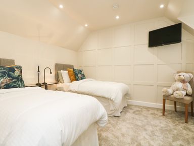 A bedroom with two single beds pillows a bedside table a chair with a teddy bear and a wall-mounted TV at Robins Nest at The Shire Inn in Killivose near Camborne