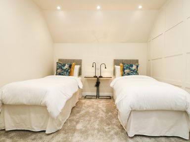 A bedroom with two single beds with cushions and a shared nightstand with lamps in between at Robins Nest at The Shire Inn Killivose near Camborne