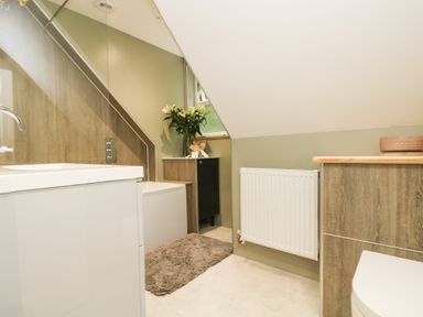 A bathroom with a bathtub, sink, radiator, cabinet with flowers, and a toilet at Robin's Nest at The Shire Inn in Killivose near Camborne