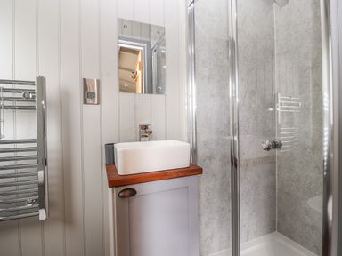 A bathroom with a glass shower enclosure a white rectangular sink on a wooden countertop and a heated towel rail at The Moorhen Retreat Nantmawr near Trefonen
