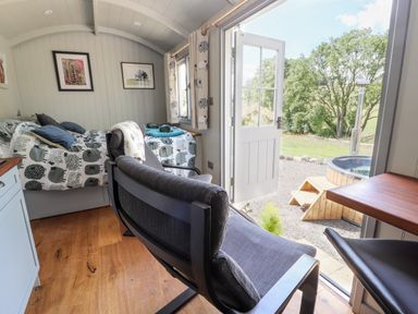 A bedroom with two single beds a chair and an open door leading outside to a wooden hot tub at The Moorhen Retreat in Nantmawr near Trefonen
