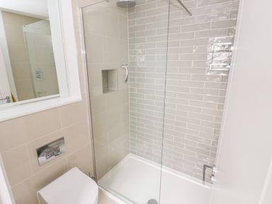 A bathroom with a shower area with glass door and a toilet at 21 The Rest in Porthcawl