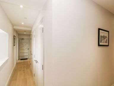 A hallway with wooden floor white walls and doors and a framed picture on the wall at 21 The Rest in Porthcawl