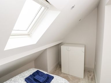 A small room with a skylight window a bed with folded blue towels and a white cabinet at 21 The Rest in Porthcawl