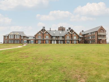 A large brick building with multiple windows and a green lawn in front at 21 The Rest in Porthcawl