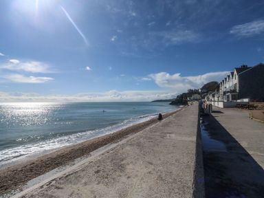 A view of the sea and beach with a concrete promenade and houses along the right side at Wrens Nest in Slapton