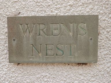 A sign displaying the name WREN'S NEST at Wrens Nest in Slapton