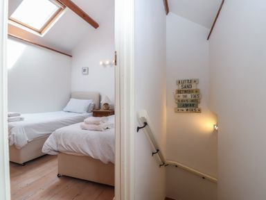 A bedroom with two beds and a staircase at Wrens Nest in Slapton