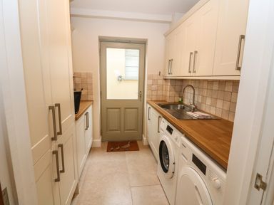 A utility room with cabinets a sink washing machine and dryer at Tawny Cottage in Fulbrook near Burford