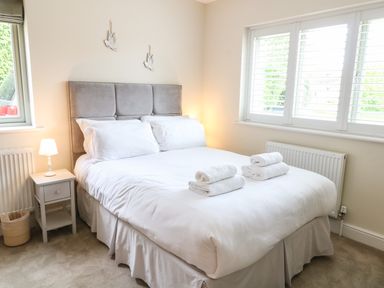 A bedroom with a double bed with white linens and folded towels on it at Tawny Cottage in Fulbrook near Burford