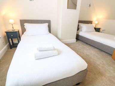 A bedroom with two single beds bedside tables and lamps at Tawny Cottage in Fulbrook near Burford