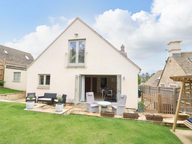 A patio with outdoor chairs and tables in the backyard of a house at Tawny Cottage in Fulbrook near Burford