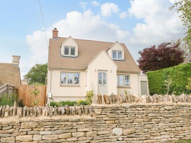 An exterior view of a house with a stone wall and a wooden gate at Tawny Cottage Fulbrook near Burford