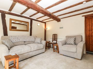 A living room with beige sofa and armchair wooden beams on ceiling and walls at 1 Old Thatch Kilve