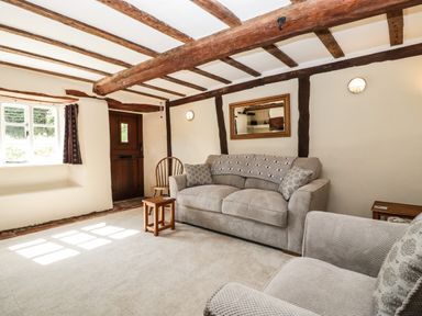 A living room with wooden beams on the ceiling sofas a wooden chair and a window at 1 Old Thatch in Kilve