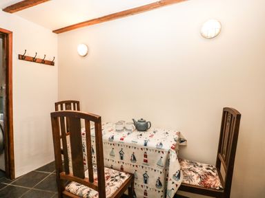 A dining area with a table covered by a patterned tablecloth and four wooden chairs at 1 Old Thatch Kilve