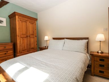 A bedroom with a double bed two bedside tables each with a lamp and wooden wardrobe and chest of drawers at 1 Old Thatch in Kilve