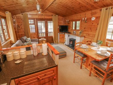 A wooden interior living room with kitchen counter tea sugar coffee canisters dining table with chairs and a sofa at Heritage Park Stepaside near Kilgetty