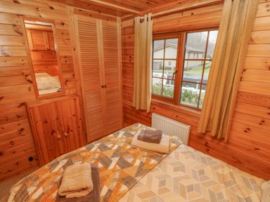 A bedroom with a bed towels wardrobe mirror and a window showing an outdoor view at Heritage Park Stepaside near Kilgetty