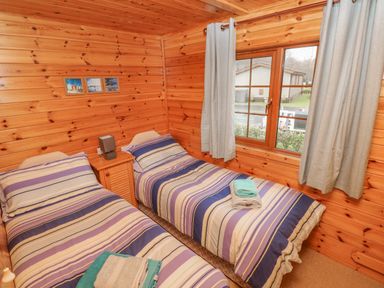 A bedroom with two single beds and a window at Heritage Park Stepaside near Kilgetty