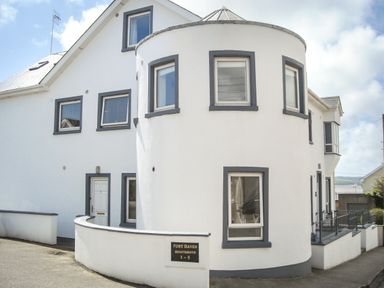 The exterior of a white building with gray window frames and a curved wall at Apartment One in Duncannon County Wexford
