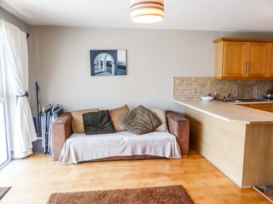 A sofa with cushions beside a kitchen counter in a living area at Apartment One in Duncannon County Wexford