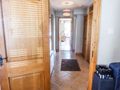 A hallway with tiled floor a rug and wooden doors leading to a room with a table and chairs at Apartment One in Duncannon County Wexford