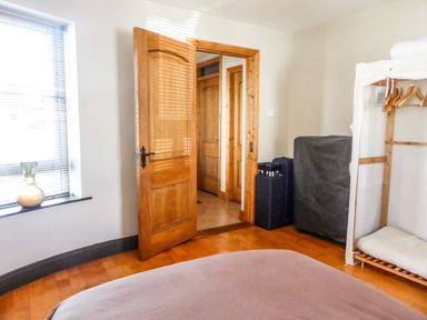 A bedroom with wooden doors a window with blinds a vase an open closet with hangers and folded linens at Apartment One Duncannon County Wexford