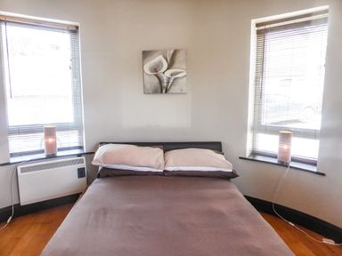 A bedroom with a bed between two windows with lamps on the window sills at Apartment One in Duncannon County Wexford