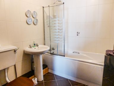 A bathroom with a toilet a sink a bathtub with a shower screen and four circular mirrors on the wall at Apartment One in Duncannon County Wexford