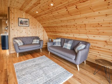 A wooden paneled living room with two gray sofas and a rug at Bluebell in St Harmon near Rhayader